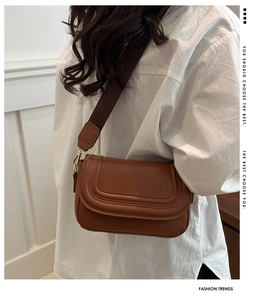 Detail of caramel suede saddle bag featuring multi-row stitching and wide woven strap