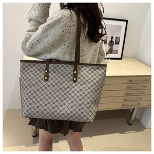 Detail of vintage canvas tote with brown leather straps worn by a model in a home setting