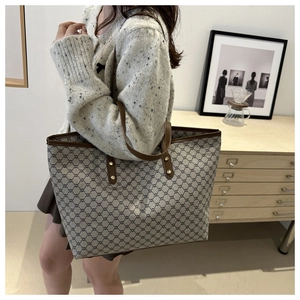Model wearing large canvas tote bag with brown leather straps and vintage floral pattern