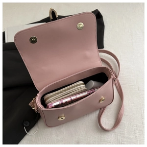 Detail view of pink leather flap bag interior with black lining and golden magnetic clasp