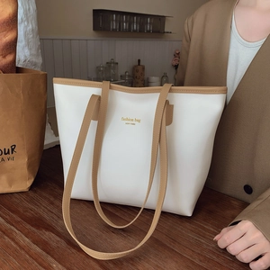 White leather tote bag with khaki handles featuring New York gold lettering on wooden desk