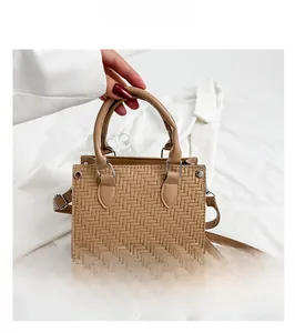 Detail of khaki woven texture handbag featuring polished silver metal hardware and round handle