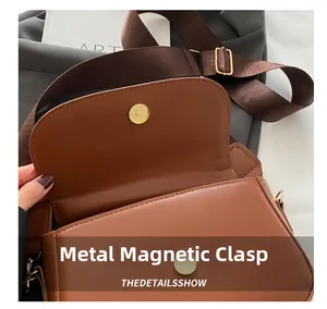 Close-up of golden magnetic snap closure on a vintage brown PU leather crossbody bag