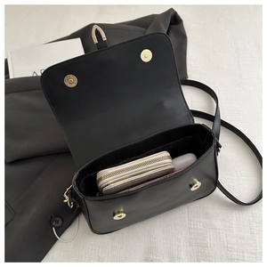 Top-down view of the black leather square bag's interior storage and magnetic clasp