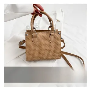 Detail of woven brown tote bag with metal rivets and phone for size comparison