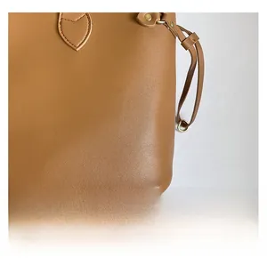 Detailed close-up of brown textured leather tote with premium gold-tone metal hardware