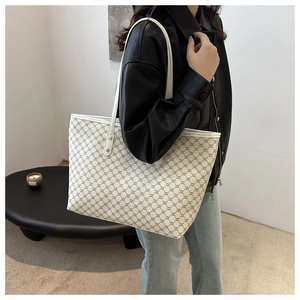 Side view of large tote bag with classic geometric pattern and brown leather handles