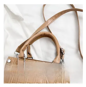 Detail of brown woven tote bag showing texture, silver metal clasp and handle stitching