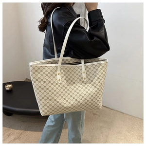 Close-up of large tote bag showing brown geometric pattern and white leather handles
