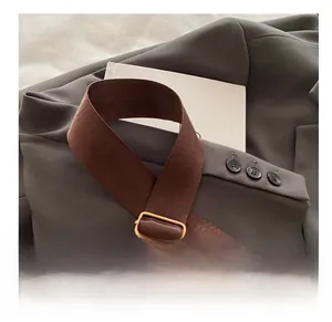 Detail of brown woven strap with golden adjustable metal buckle on a grey suit jacket