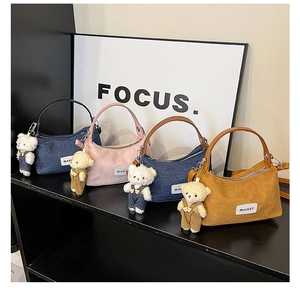 Detail of trendy denim and corduroy shoulder bags with cute bear charm and logo patch