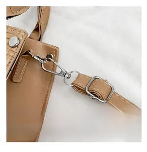 Detailed close-up of premium silver metal buckle and stitching on brown leather handbag