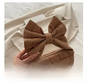 Detail of caramel quilted handbag featuring an oversized bow handle and secure zipper