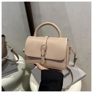 Close-up of light beige tote bag featuring litchi texture and gold buckle detail
