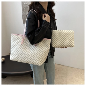 Detail of a large monogram tote bag with pink leather trim shown in a minimal setting