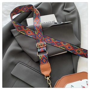 Detail of colorful geometric woven bag strap with leather ends and metal hooks
