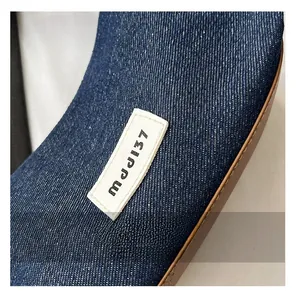 Macro view of denim fabric texture with brown leather trim and rectangular logo label