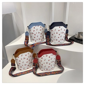Detail of trendy cherry print bucket bags with colorful geometric patterned shoulder straps