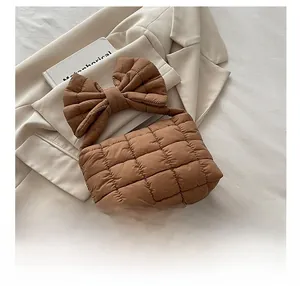 Detail show of brown quilted down handbag with a large decorative bow handle and soft texture