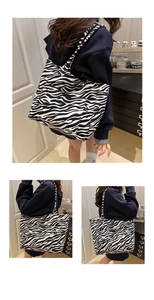 Detail of large zebra print canvas tote bag with outer pocket on a navy hoodie