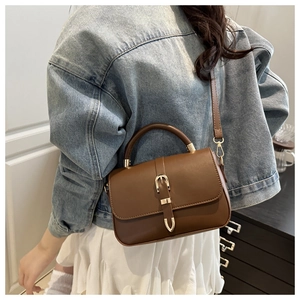 Brown leather crossbody bag with gold buckle shown on model for daily commuting style