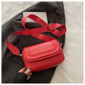 Dettaglio della borsa a tracolla rossa con cuciture curve e accessori metallici dorati