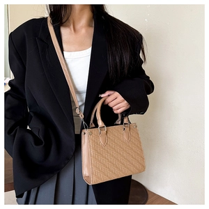 Detail of woven texture on khaki tote bag with adjustable leather shoulder strap