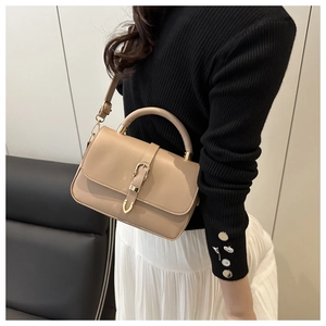 Detail of khaki leather handbag with metal clasp and adjustable strap for commuting