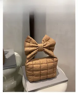 Dettaglio di borsa a mano marrone trapuntata con un grande manico a fiocco decorativo