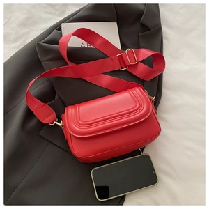Dettaglio borsa rossa in similpelle con patta trapuntata e ampia tracolla su blazer
