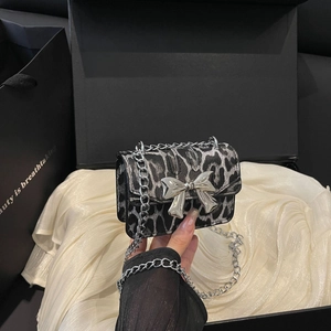 Mini leopard print chain bag with silver bow clasp on elegant silk background