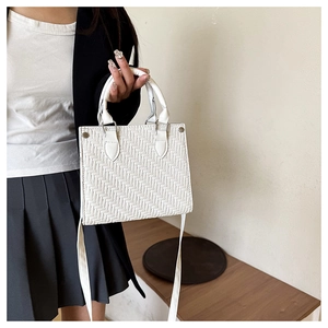 Detailed close-up of white woven texture on a structured faux leather tote handbag
