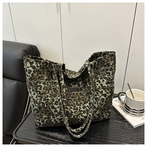 Detail of leopard print canvas tote bag with reinforced handles on a dark tabletop