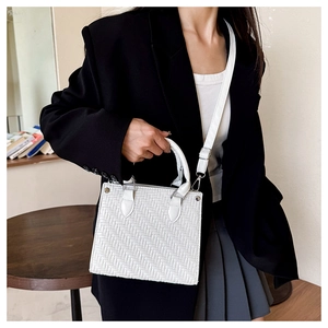Close-up of white woven leather handbag with minimalist handle and detachable shoulder strap