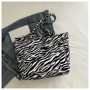 Detail of canvas tote bag featuring black and white zebra print with front pocket