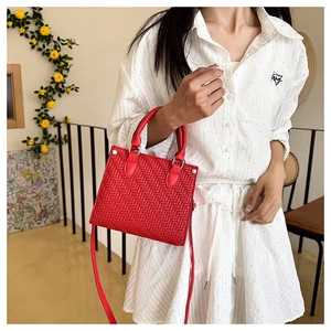 Detail of red woven texture tote bag with silver rivets and dual handle straps