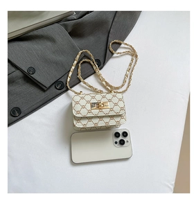 Mini flap crossbody bag with chain strap compared with phone to show compact size