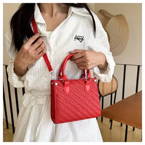 Detail of red woven faux leather tote bag with V-pattern and silver metal hardware