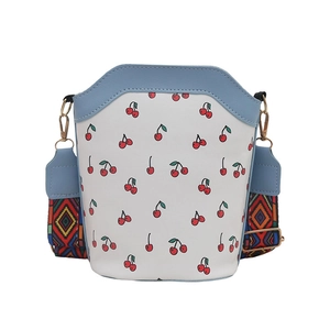 Minimalist bucket bag with cherry print and colorful geometric woven shoulder strap