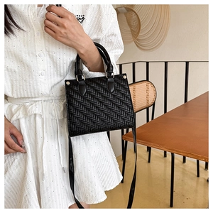 Detail view of black woven tote bag featuring high-quality texture and metal rivet accents