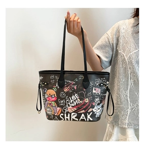 Detail of black leather tote bag with colorful graffiti art and dual shoulder straps