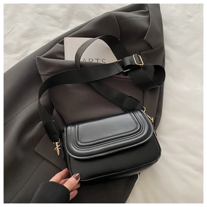 Dettaglio borsa a tracolla in pelle nera con cuciture curve e fibbie dorate lucide