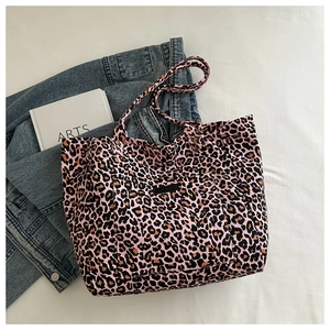 Detailed view of pink leopard print canvas tote bag on white cloth with denim jacket