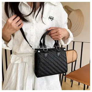 Detail of black woven tote bag featuring V-shaped texture and silver metal rivets decoration