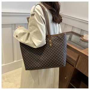 Large tote bag with brown chain pattern and leather straps shown on a model