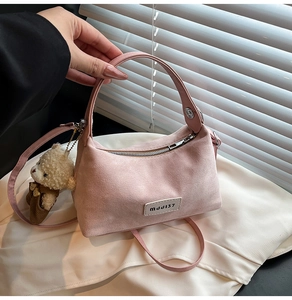 Close-up of pink suede handbag with cute plush bear charm and metallic zipper detail