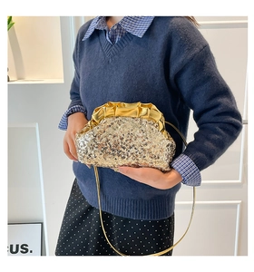 Detailed view of shimmering gold sequins and ruched leather on a luxury evening clutch