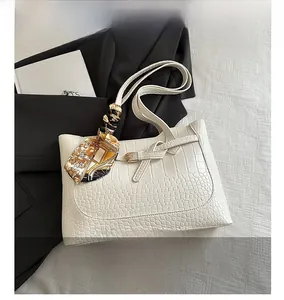 Close-up of white crocodile pattern tote bag with printed silk scarf on the handle