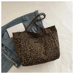 Flat lay of a leopard print canvas tote bag with outer pocket on a white background