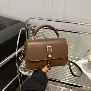 Vintage brown leather crossbody bag with top handle and gold hardware in urban setting